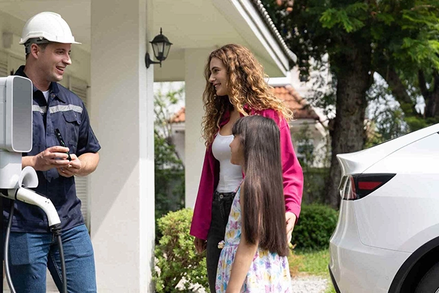 Electrician Discussing EV Charger Installation with Family Near White Car