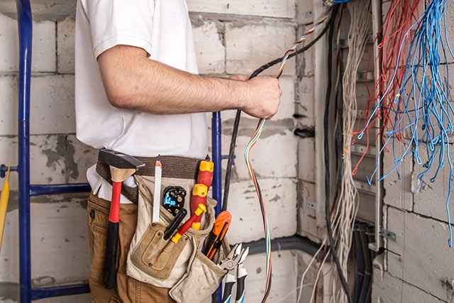 Electrician in White Shirt Holding Wires in Unfinished Building