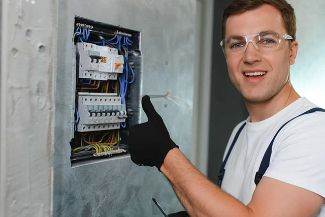 Electrician Thumbs Up Next to an Electrical Panel During Repairs